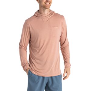 Man wearing a pink hoodie and blue shorts, smiling, hands in pockets